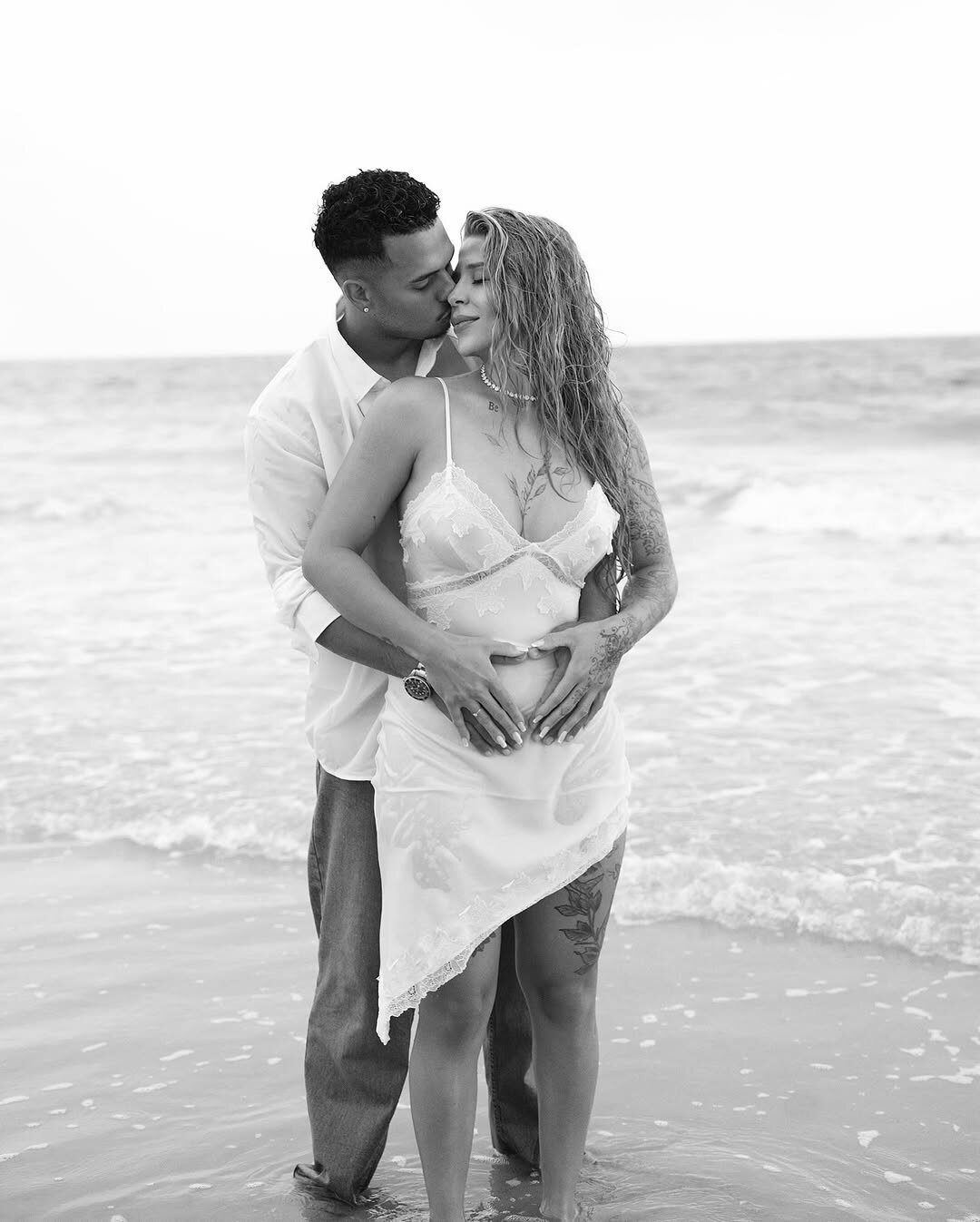 Casal abraçado à beira-mar, em tons claros